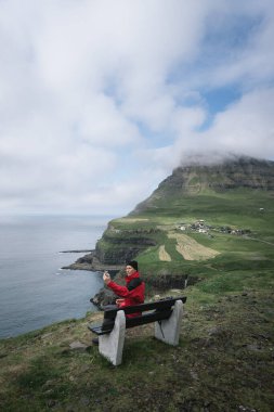 Faroe Adaları, Vagar adasındaki Gasadalur köyünün önünde bir adam selfie çekiyor.