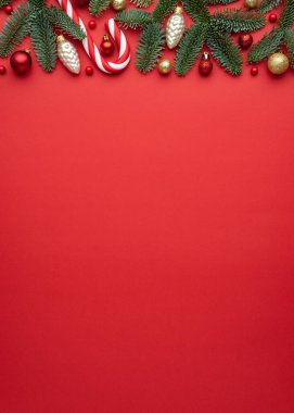Kırmızı arka planda Noel ve Yeni Yıl sınır çerçevesi. Köknar dallarının, Noel balolarının ve baston şekerlerin şenlikli dekoru.