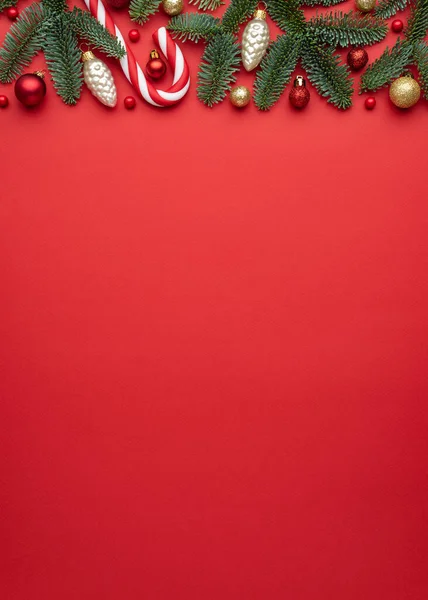 赤い背景にクリスマスと新年の国境フレーム モミの枝 クリスマスボール キャンディー杖のお祝いの装飾 — ストック写真
