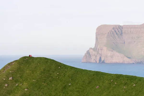 游客们喜欢坐在卡鲁塞岛山上的法罗群岛的自然美景 — 图库照片