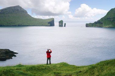Gezgin, Faroe Adaları 'ndaki Drangarnir deniz yığınlarını ve Tindholmur adasını fotoğraflıyor.