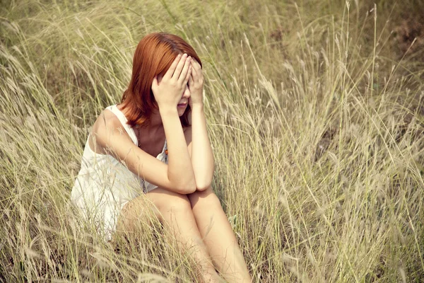 잔디에서 슬픈 빨간 머리 소녀. — 스톡 사진