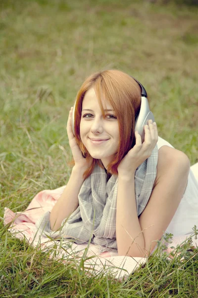 Chica de la moda joven con auriculares tumbados en la hierba verde —  Fotos de Stock