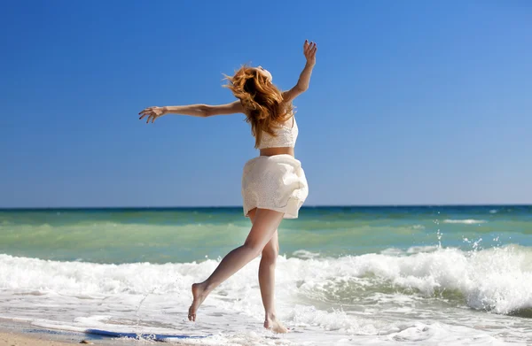 Young redhead girl jumping at the beach. — Stock Photo, Image