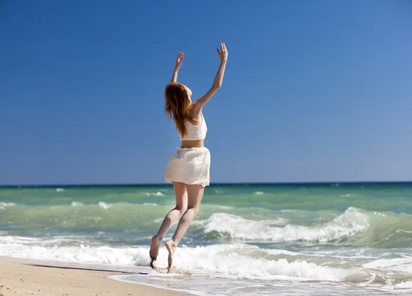 Jovem ruiva pulando na praia . — Fotografia de Stock