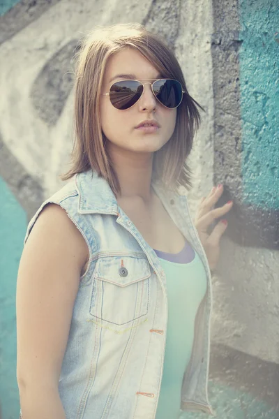 Tiener meisje in zonnebril in de buurt van graffiti muur. — Stockfoto