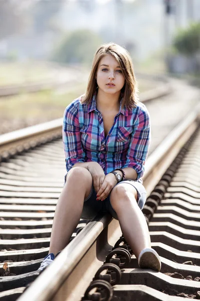 Triest tiener meisje zit op spoorweg. — Stockfoto