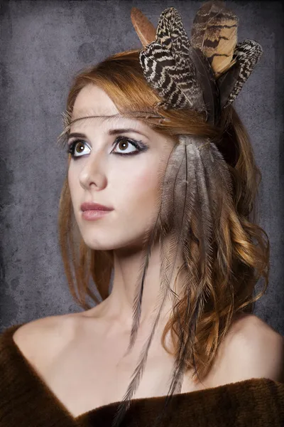 Stil rothaarige Mädchen mit Federn auf dem Kopf. Studioaufnahme. — Stockfoto