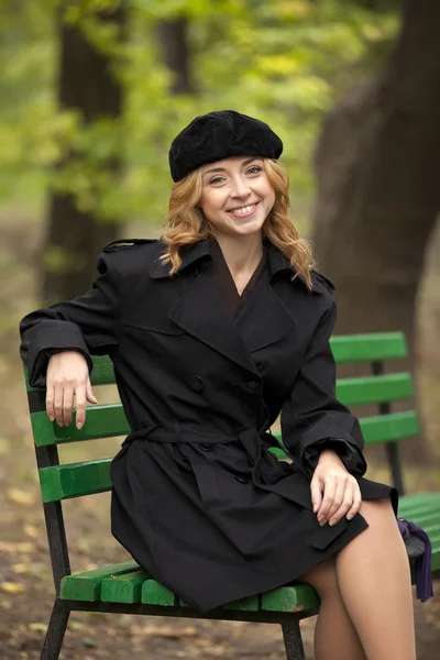 Style redhead girl sitting at bench in autumn park. — Stock Photo, Image
