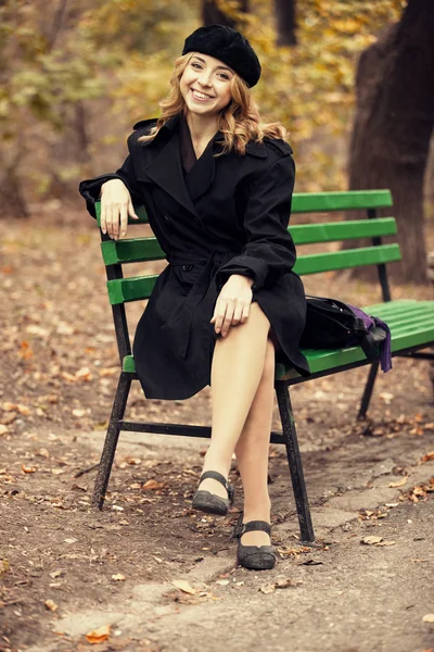 Rotschopf-Mädchen sitzt auf Bank im Herbst-Park. — Stockfoto