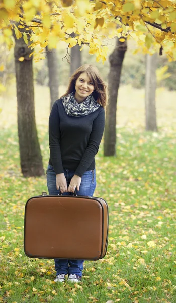 Piękna dziewczyna z walizka w jesień park. — Zdjęcie stockowe