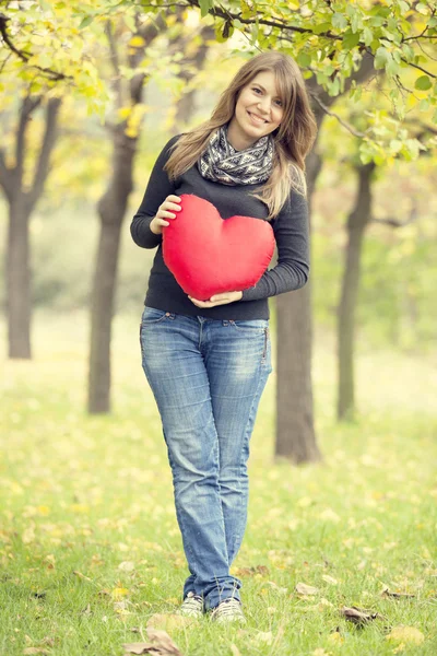 Rusovláska dívka s hračkou srdce na podzimní park. — Stock fotografie