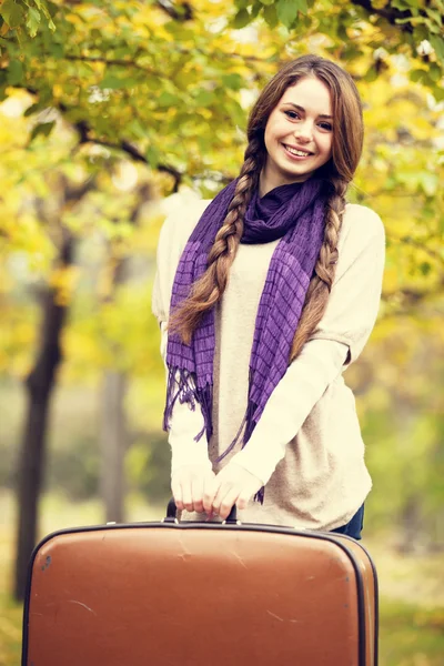 Mooi meisje met koffer in herfst park. — Stockfoto