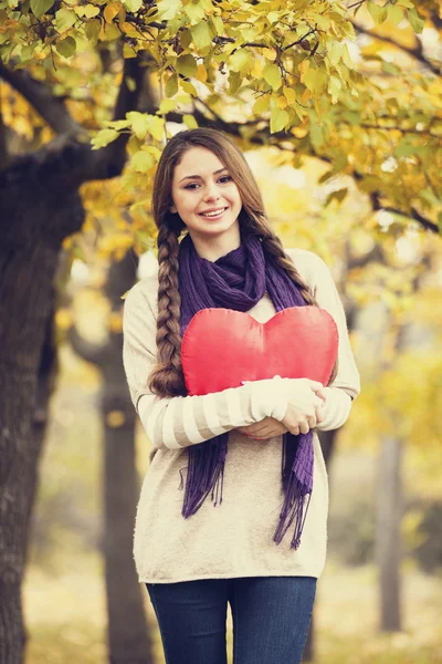 Redhead girl with toy heart at autumn park. — Stockfoto