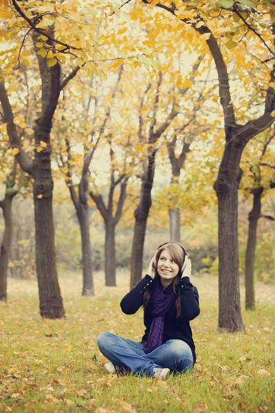 Moda młoda dziewczyna ze słuchawkami na jesień park. — Zdjęcie stockowe