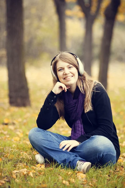 Junges Modemädchen mit Kopfhörern im Herbstpark. — Stockfoto