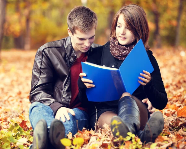 Hermosa pareja con cuaderno en el parque de otoño . — Foto de Stock