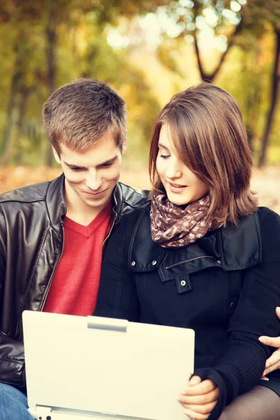 Beautiful couple with laptop at autumn park. — Stock Photo, Image