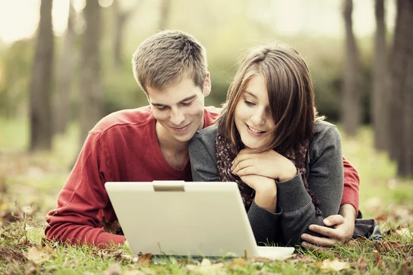 Beautiful couple with laptop at autumn park. — Stock Photo, Image