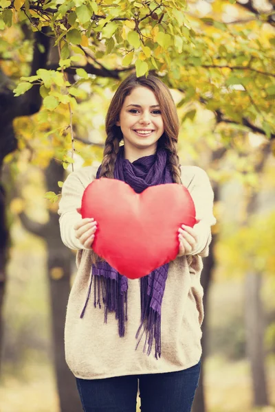 Redhead girl with toy heart at autumn park. Royalty Free Stock Photos