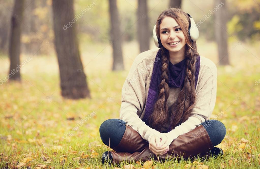 Young fashion girl with headphones at autumn park.