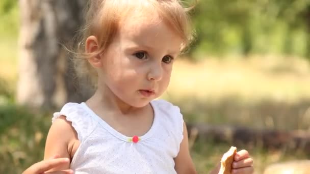 Niña comiendo galleta en el parque . — Vídeo de stock