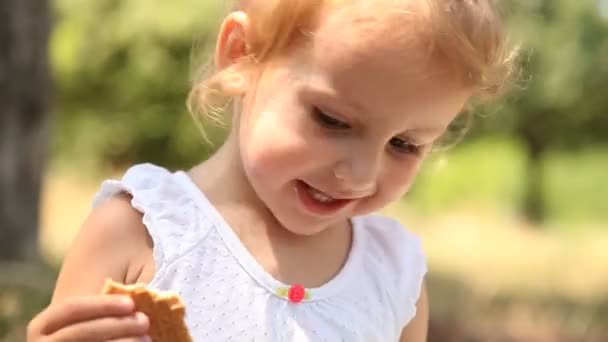 Dziewczynka jedzenie krakingu w parku. — Wideo stockowe
