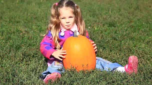 Little gardener girl with pumpkin at green grass — Stock Video
