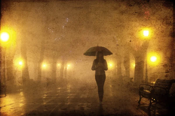 Одна дівчина з парасолькою на нічній алеї. Фото з шумом . — стокове фото