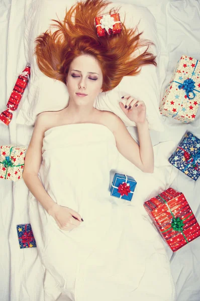 Redhead girl in bed with gifts. Photo in warm tone style. — Stock Photo, Image