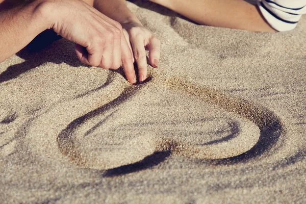 Kreslení srdce v písku. — Stock fotografie