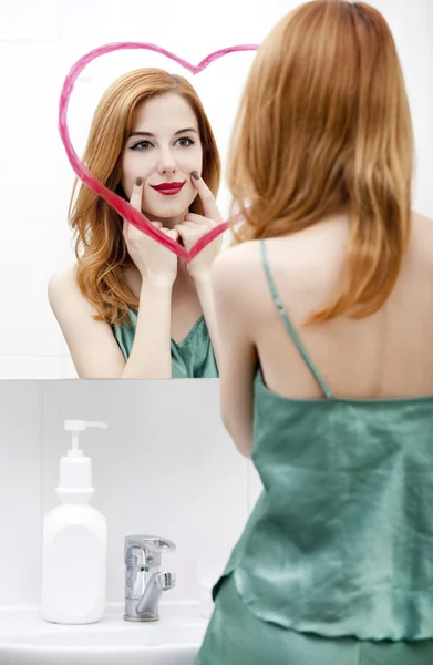 Pelirroja chica cerca del espejo con el corazón en el baño . — Foto de Stock