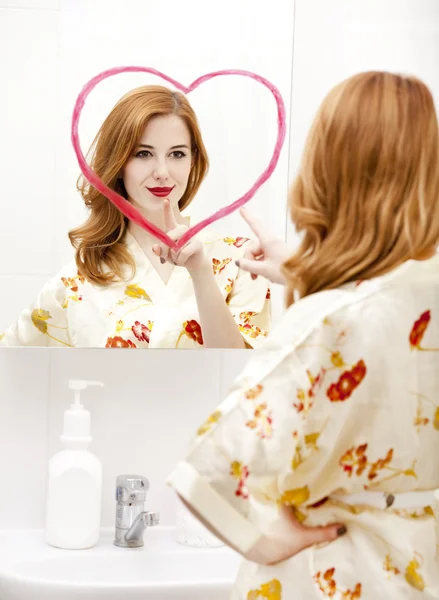 Aynanın yanındaki kızıl saçlı kız, kalbi banyoda.. — Stok fotoğraf