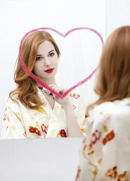 Redhead girl near mirror with heart it in bathroom. — Stock Photo, Image