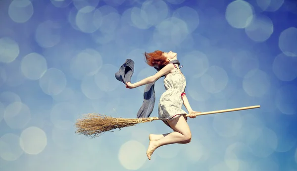 Giovane strega dai capelli rossi sulla scopa che vola nel cielo — Foto Stock