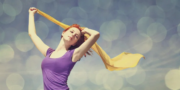 Mujer joven con los brazos abiertos mantener la seda amarilla en el viento . — Foto de Stock