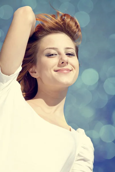 Ritratto di ragazza rossa in bianco su cielo blu con bokeh sul retro — Foto Stock