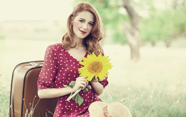 Roodharige meisje met zonnebloem op buiten. — Stockfoto