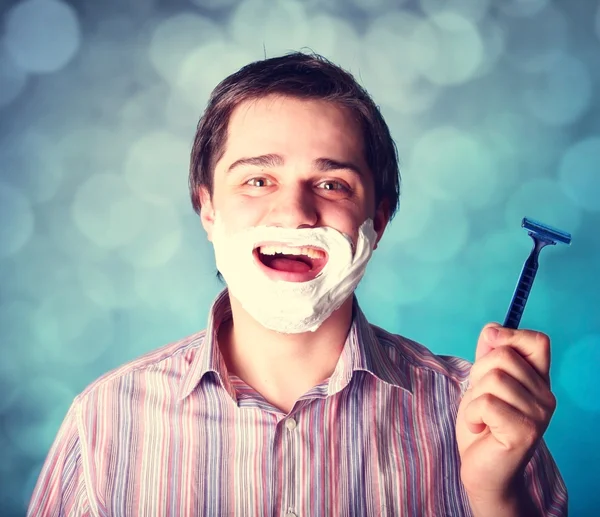 Чоловік голиться ізольовано на синьому фоні — стокове фото