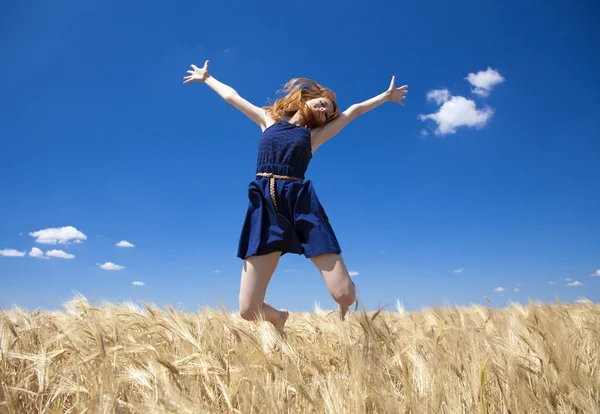 Руда дівчина на пшеничному полі в літній день. Фото з боке в б — стокове фото