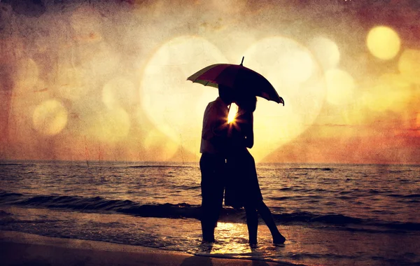 Couple embrassant sous le parapluie à la plage au coucher du soleil. Photo en o — Photo