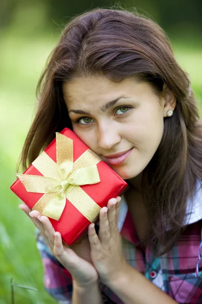 Schöne Teenie-Mädchen mit Geschenk im Park auf grünem Gras. — Stockfoto