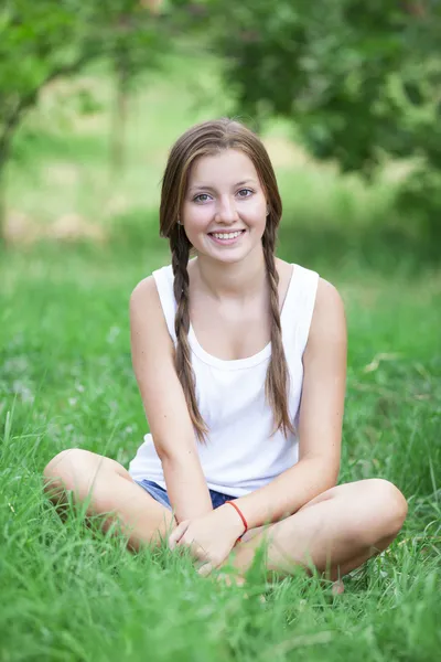 Hermosa chica adolescente en el parque en la hierba verde . — Foto de Stock