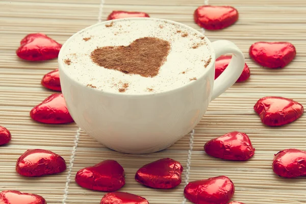 Cup of coffee with heart symbol and candy around. — Stock Photo, Image