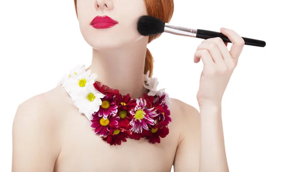 Menina ruiva bonita com flores e pincel de maquiagem — Fotografia de Stock