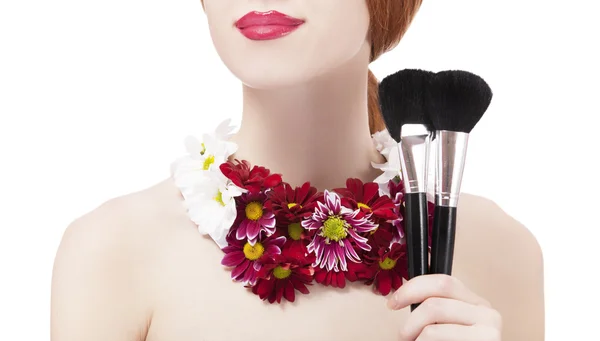 Mooi roodharig meisje met bloemen en make-up borstel — Stockfoto