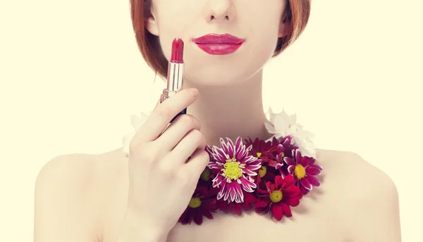 Piękny rudy dziewczyna z kwiatami, trzymając szminka — Zdjęcie stockowe