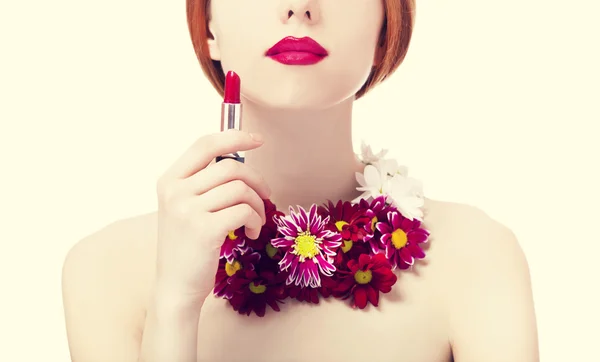 Schöne rothaarige Mädchen mit Blumen halten Lippenstift — Stockfoto