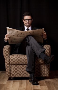 adam sigara ve vintage koltukta oturup gazete