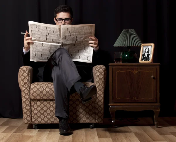 Hombre con periódico sentado en sillón vintage — Foto de Stock